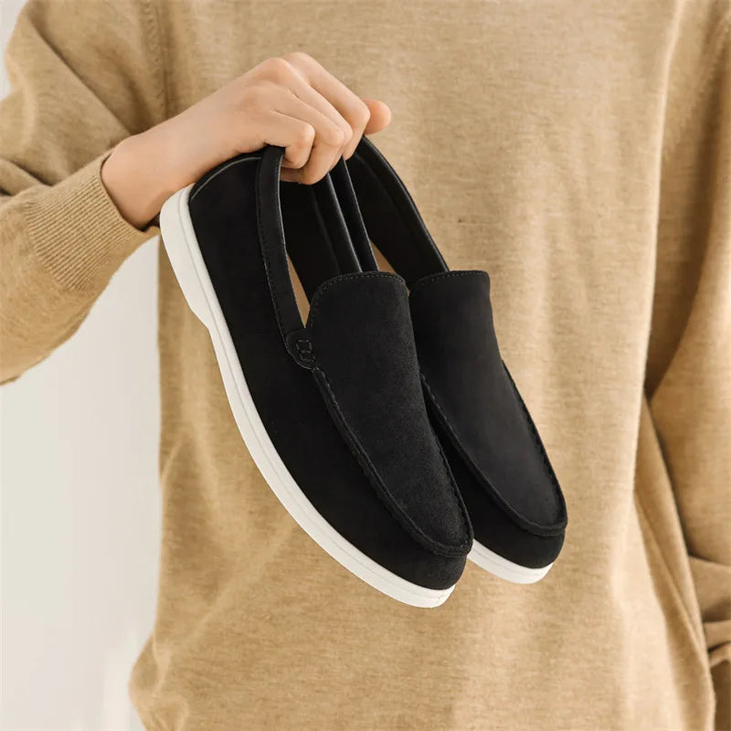 Mocassim Amalfi de camurça preta, sola branca e detalhe do cadarço com costura.
